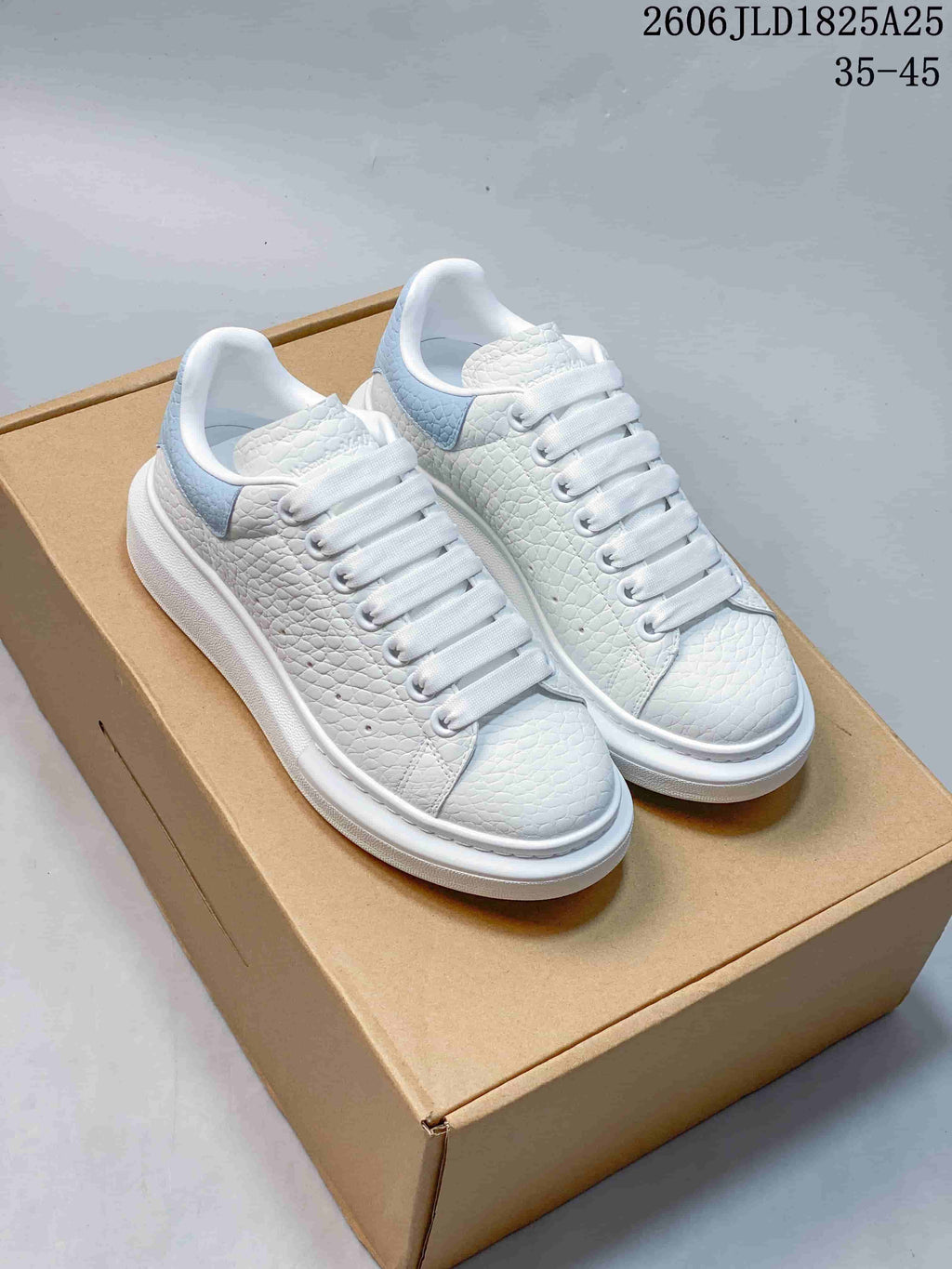 Pair of white textured sneakers with pale blue heel panels and thick white soles; size range 35–45 appears in the image.