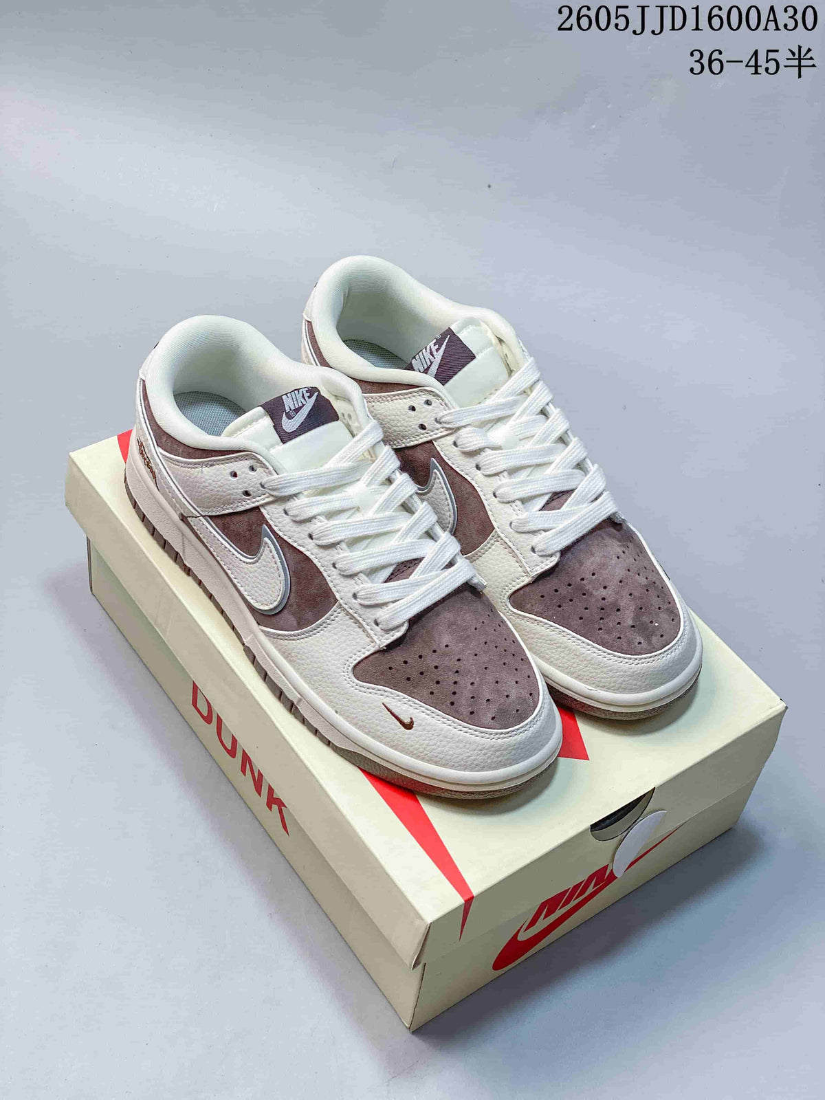 Pair of off-white and mauve-brown low-top sneakers displayed on a shoebox