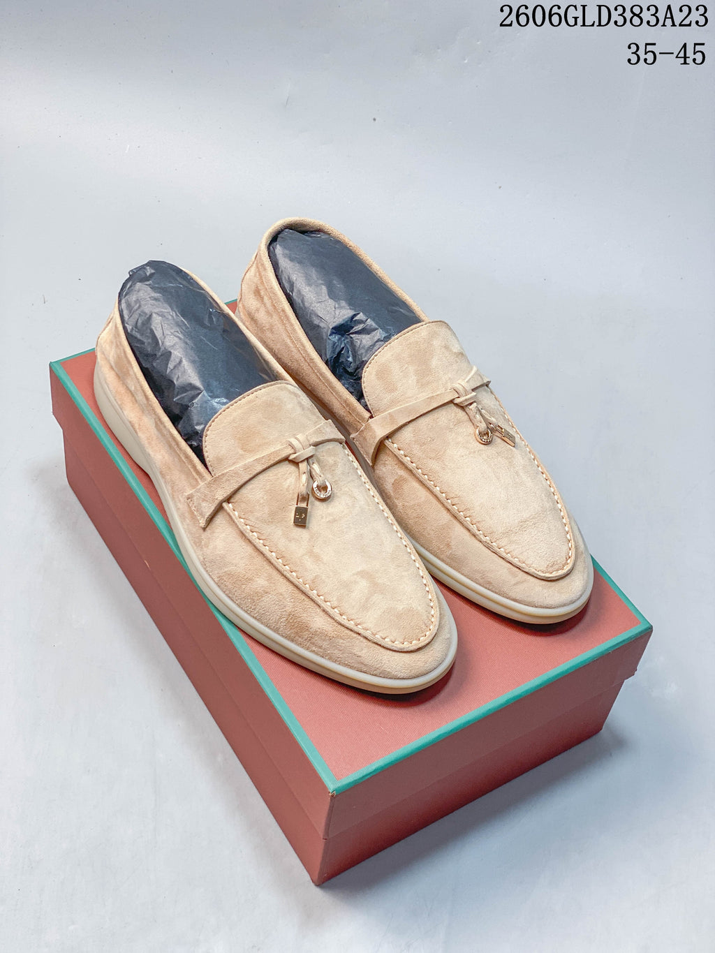 Light beige pair of strap-detail loafers with moc-toe stitching and small metal ornaments; image also displays the size range 35–45.
