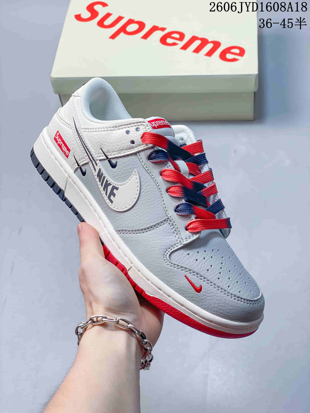 Angled side view showing grey and white panels, Nike and Supreme branding, and red and navy details.
