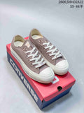 Pair of taupe low-top Converse All Star sneakers with white laces and toe caps on a Converse box