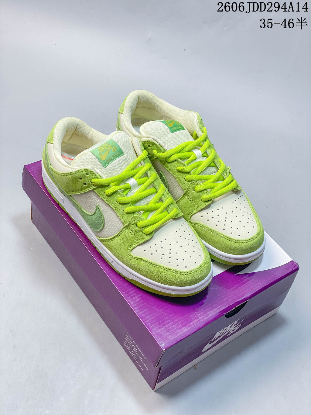 Pair of lime-green and white Nike Dunk Low SB sneakers on a purple box