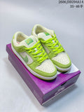 Pair of lime-green and white Nike Dunk Low SB sneakers on a purple box