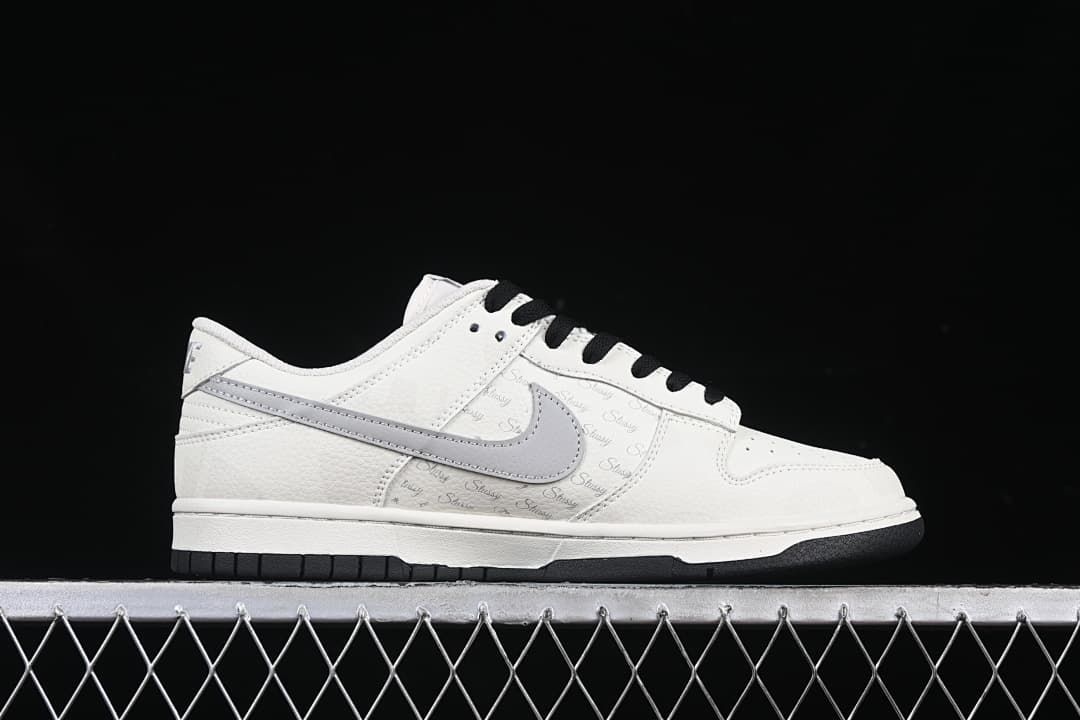 Side profile showing the white upper, grey Swoosh, Stüssy script and black outsole.