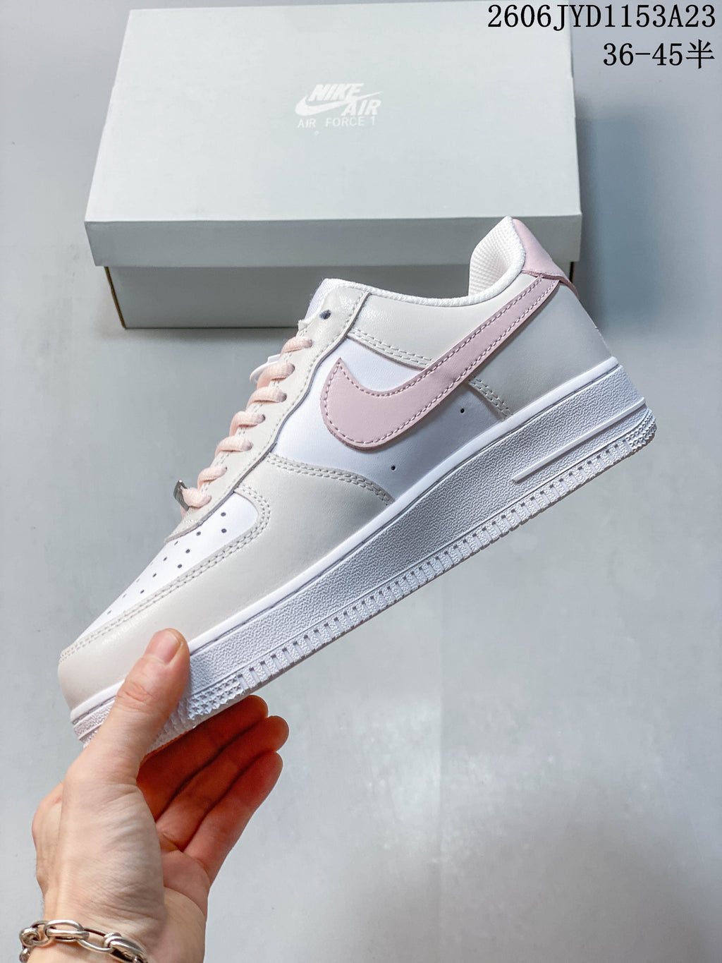 Side view of a white low-top sneaker with pale pink Swoosh and heel trim