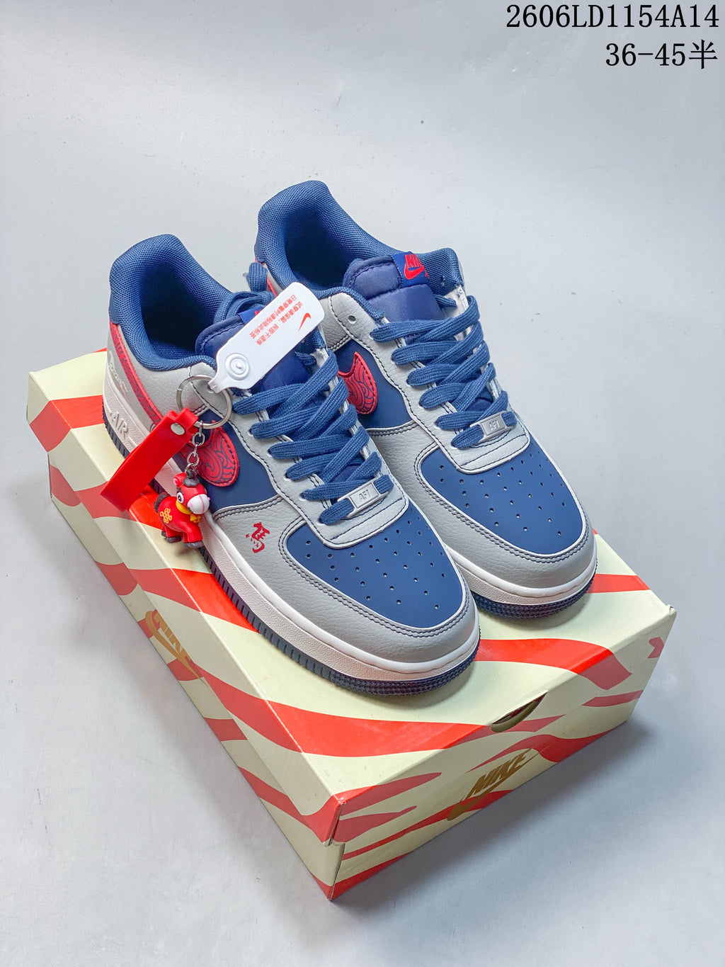 Pair of blue and grey Nike Air Force 1 ’07 Low sneakers with red accents, shown on a patterned box.
