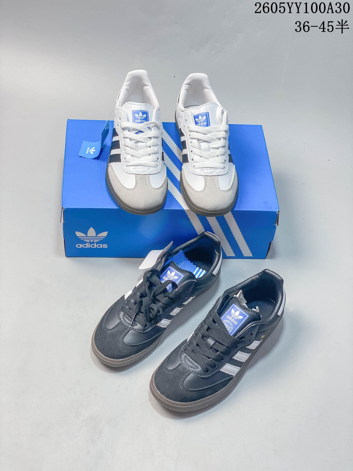 White and dark grey Adidas Samba sneakers shown together with a blue box
