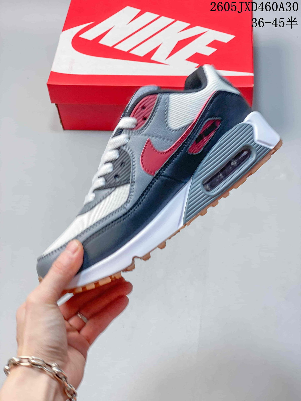 Side view of a grey, white, and red Nike Air Max 90 showing the visible heel Air unit.