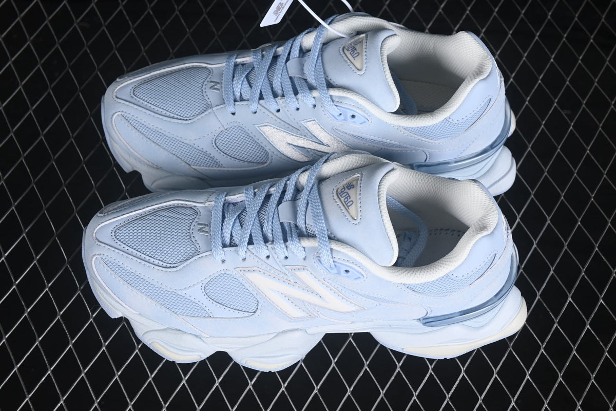 Top view of a pair of light blue and white New Balance 9060 sneakers with mesh toe boxes and laces.