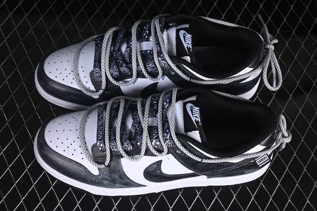 Overhead view of a pair of black-and-white low-top sneakers with patterned laces