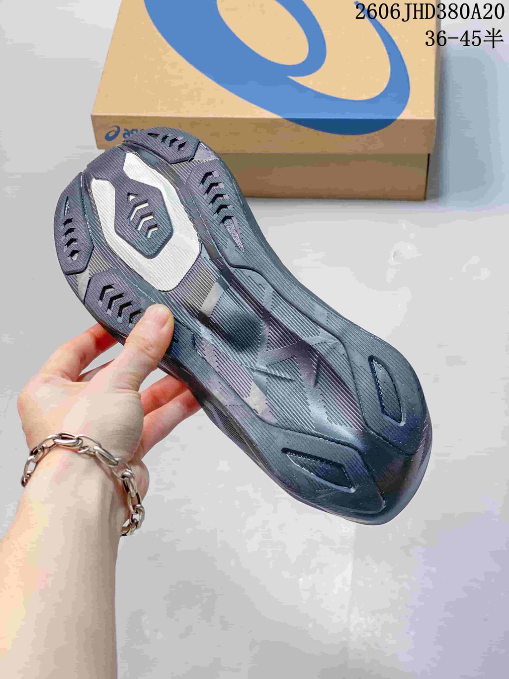Underside view showing the patterned outsole of a dark charcoal running shoe
