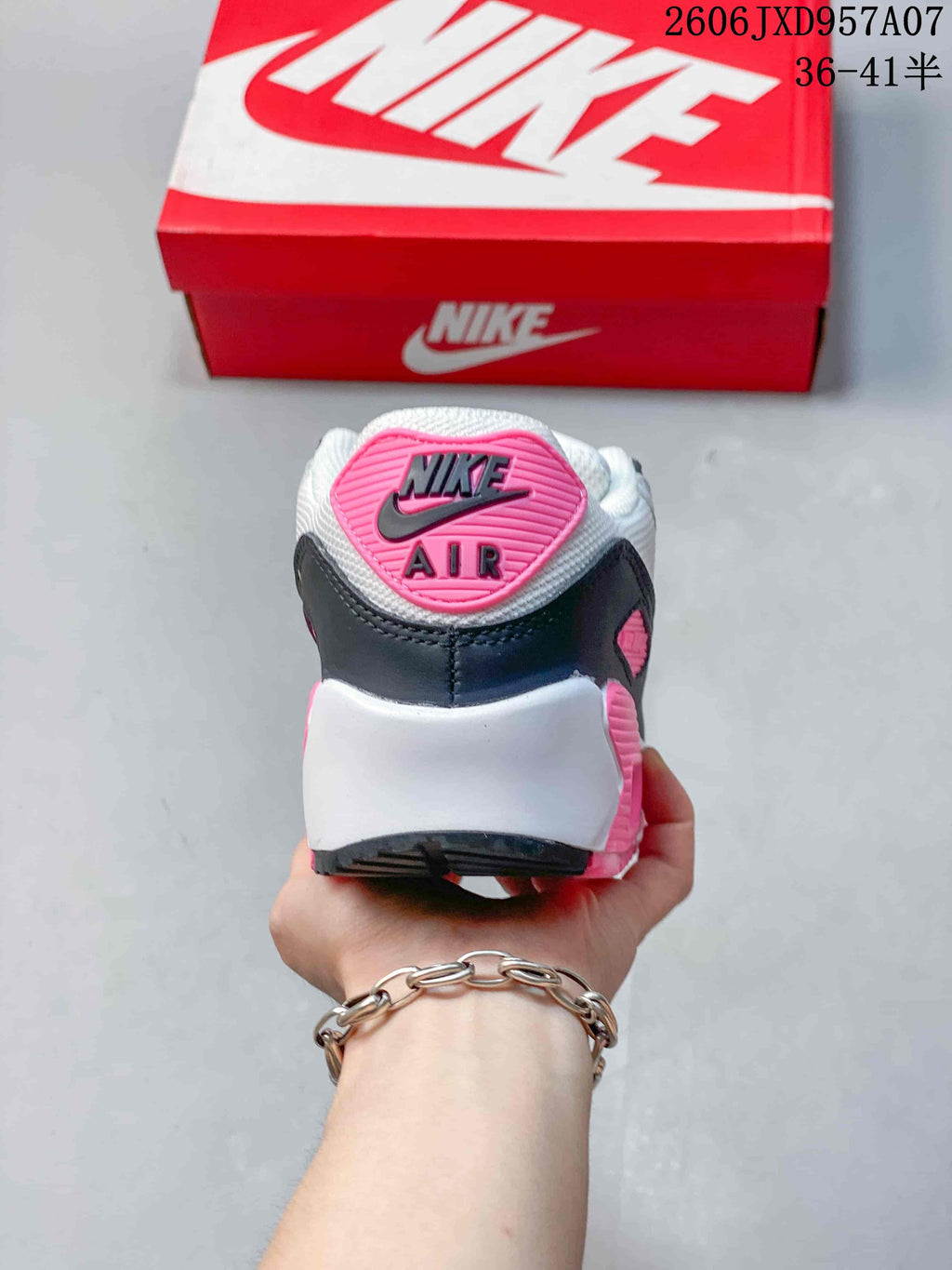 Rear view of a Nike Air Max 90 sneaker with a pink heel badge and dark heel panel