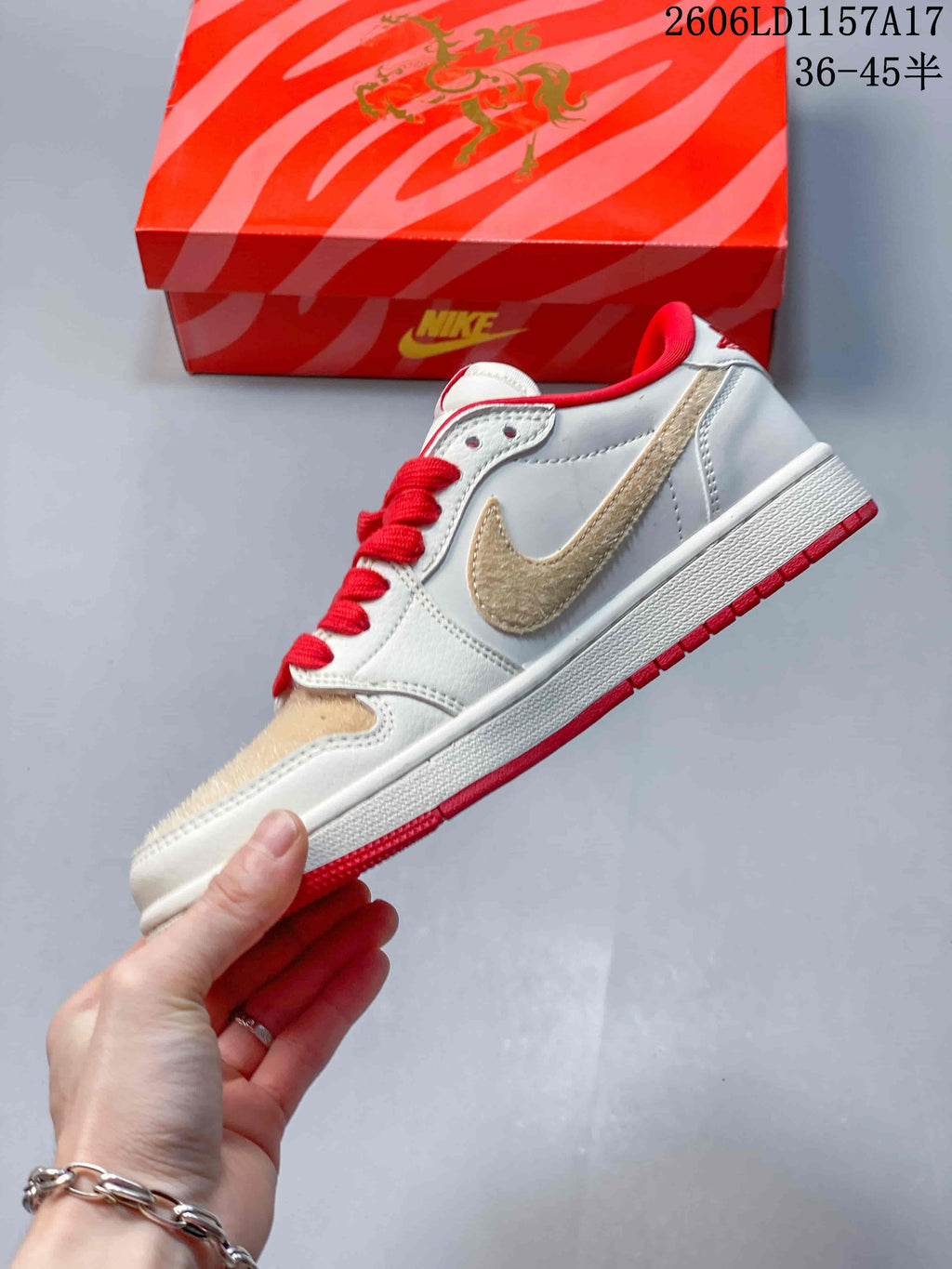 Side view of a cream low-top sneaker with tan Swoosh and red accents