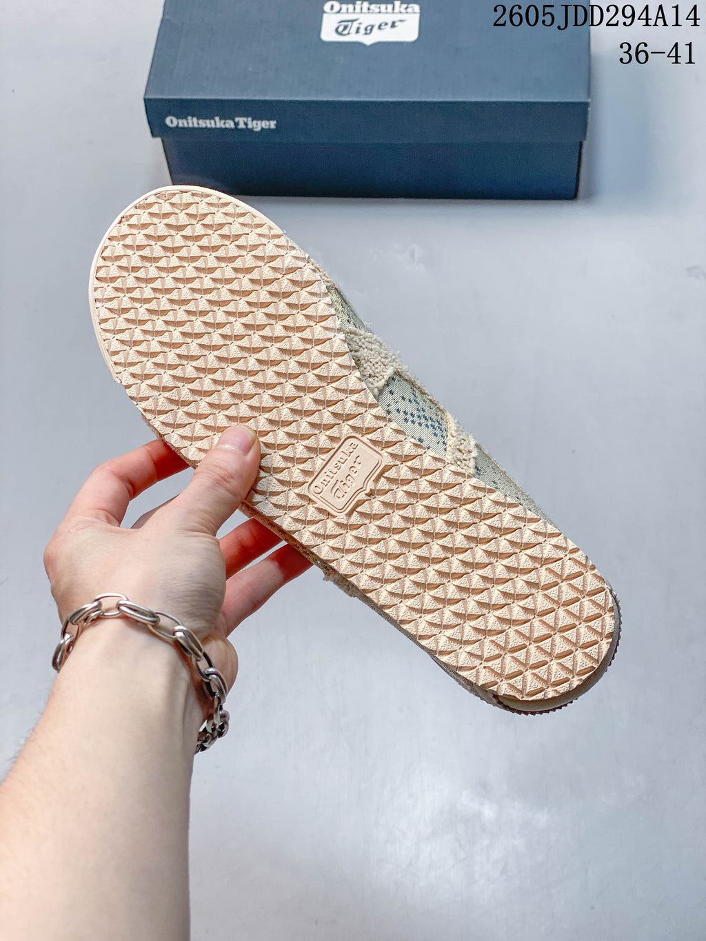 Textured outsole of a cream sneaker beside an Onitsuka Tiger shoe box