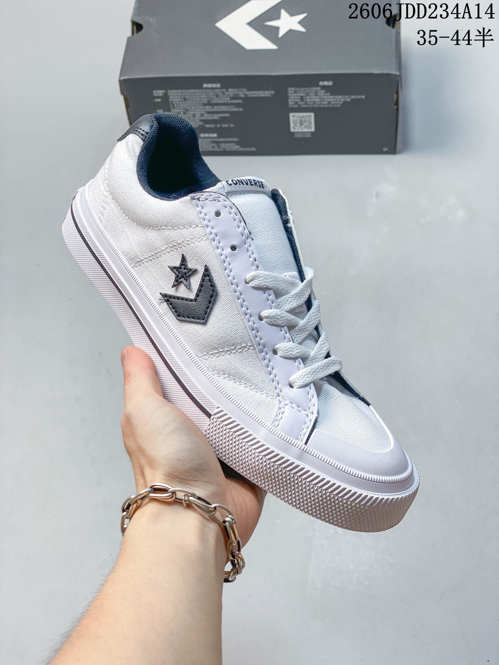 Angled view of a white Converse low-top sneaker with navy details