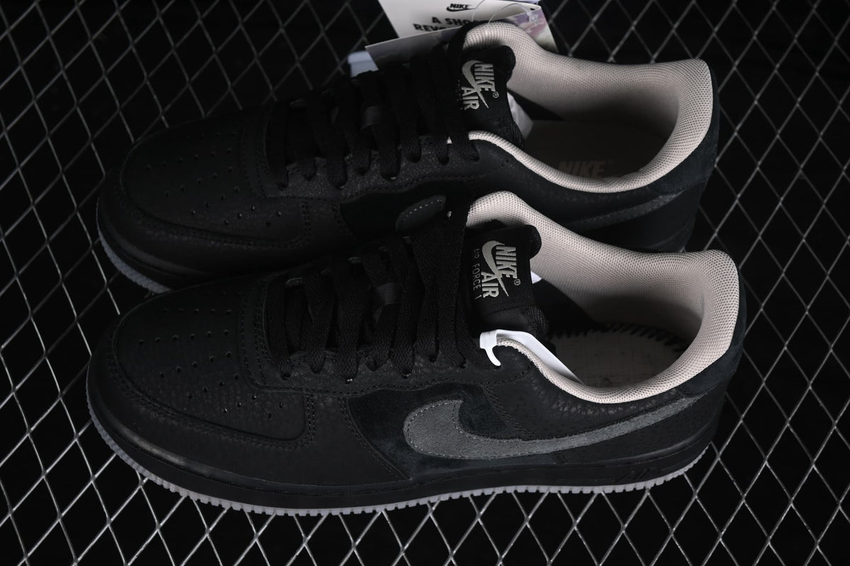 Angled view of a pair of black low-top sneakers showing the light-colored collar lining and grey Swoosh accents.