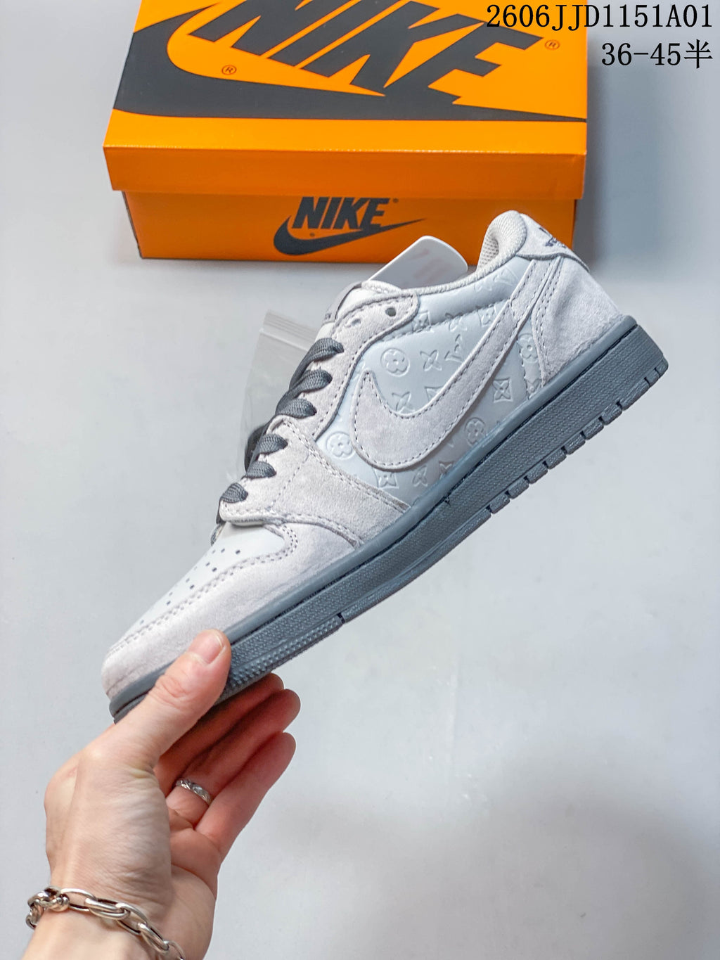 Side view of the light gray low-top sneaker with embossed patterned panels