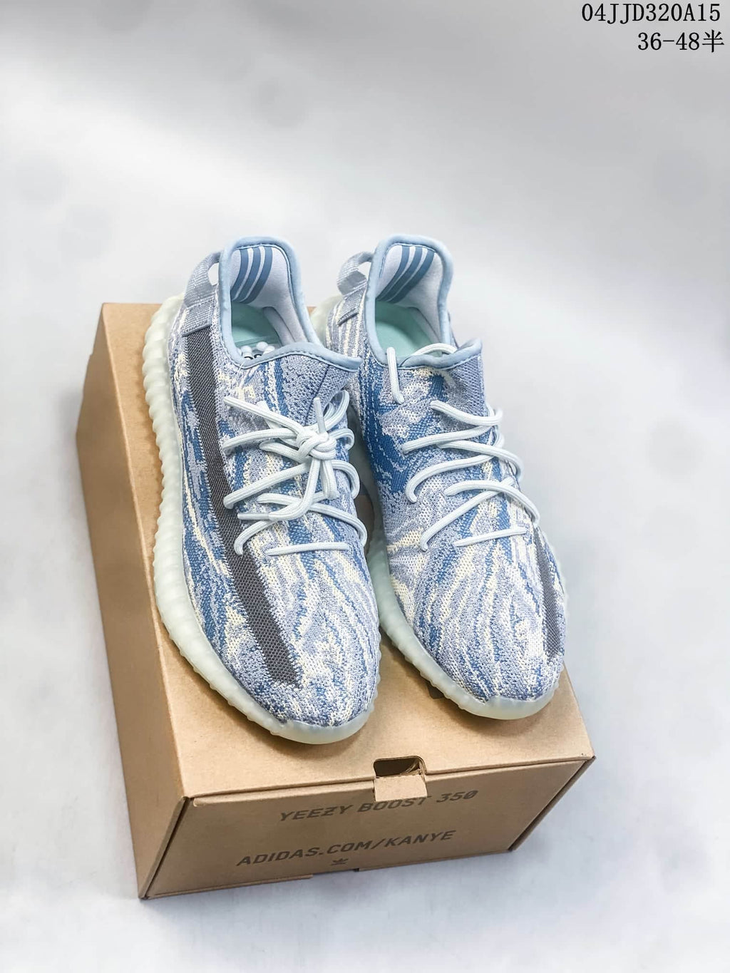 Pair of blue and cream patterned Yeezy Boost 350-style sneakers displayed on a box.