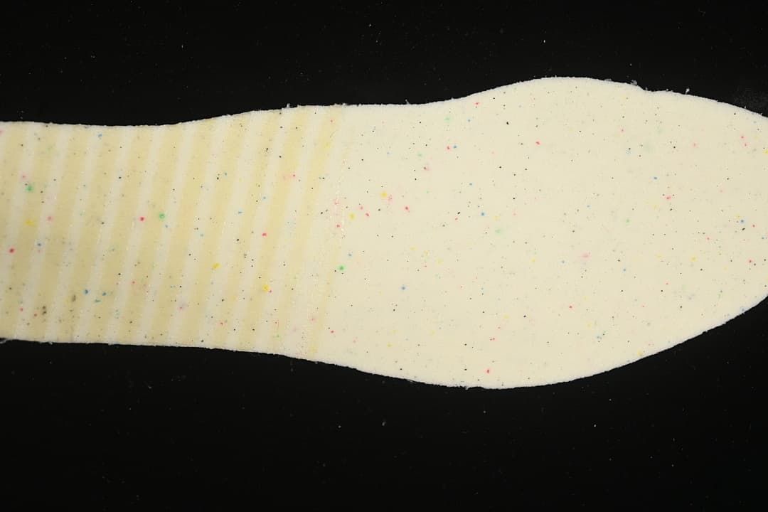 Close-up of a light-colored shoe insole with small multicolor speckles