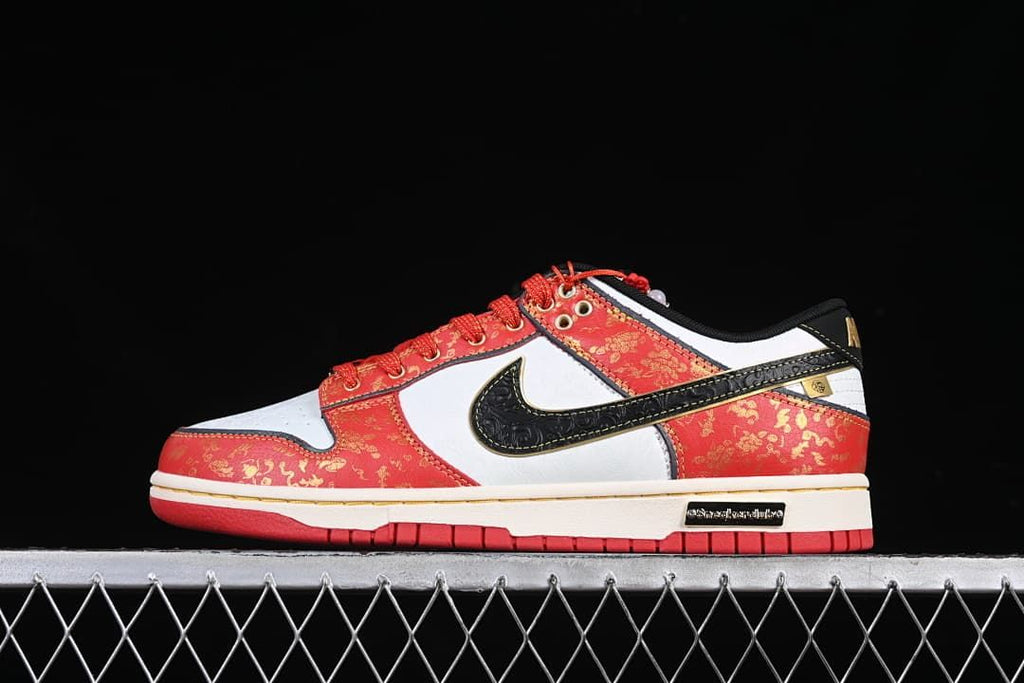 Side view of a red, white, and black low-top sneaker with gold-patterned panels