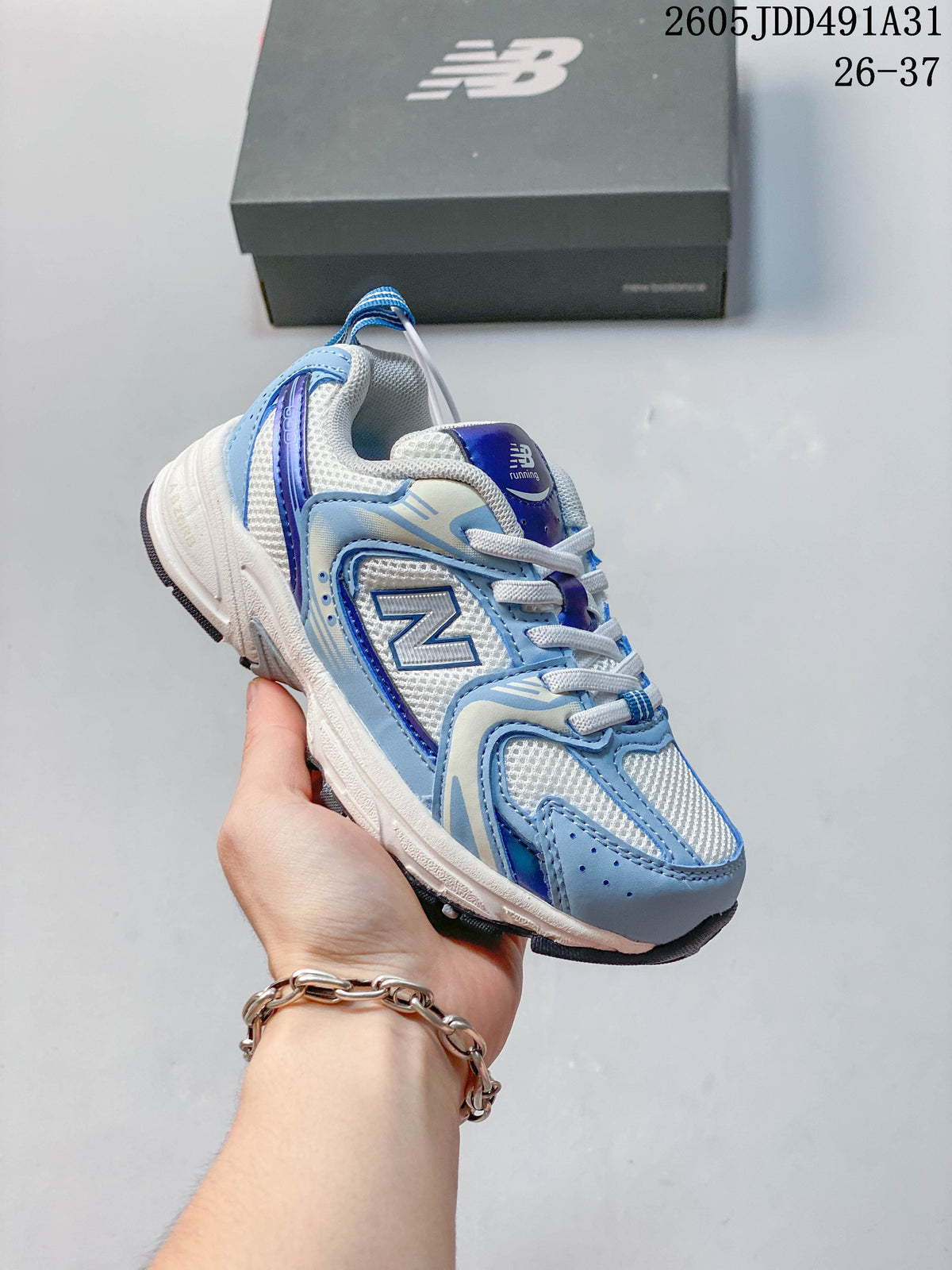 Blue and white kids' New Balance 530 lace-up sneaker shown in hand.