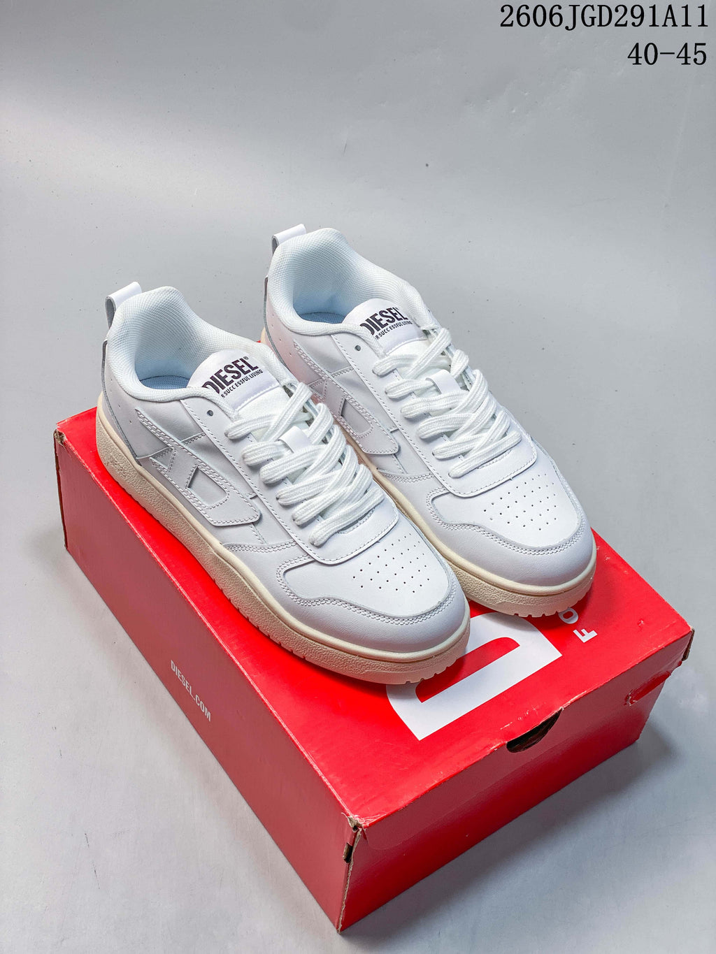 Pair of white Diesel S-Ukyo V2 low-top sneakers displayed on a red shoe box.
