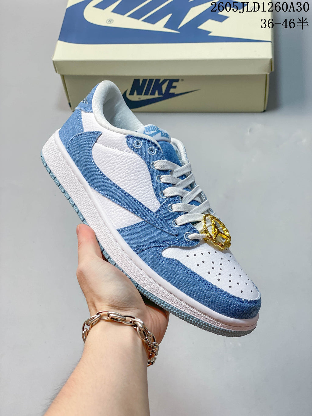 Side view of a light-blue and white low-top sneaker with a lace charm