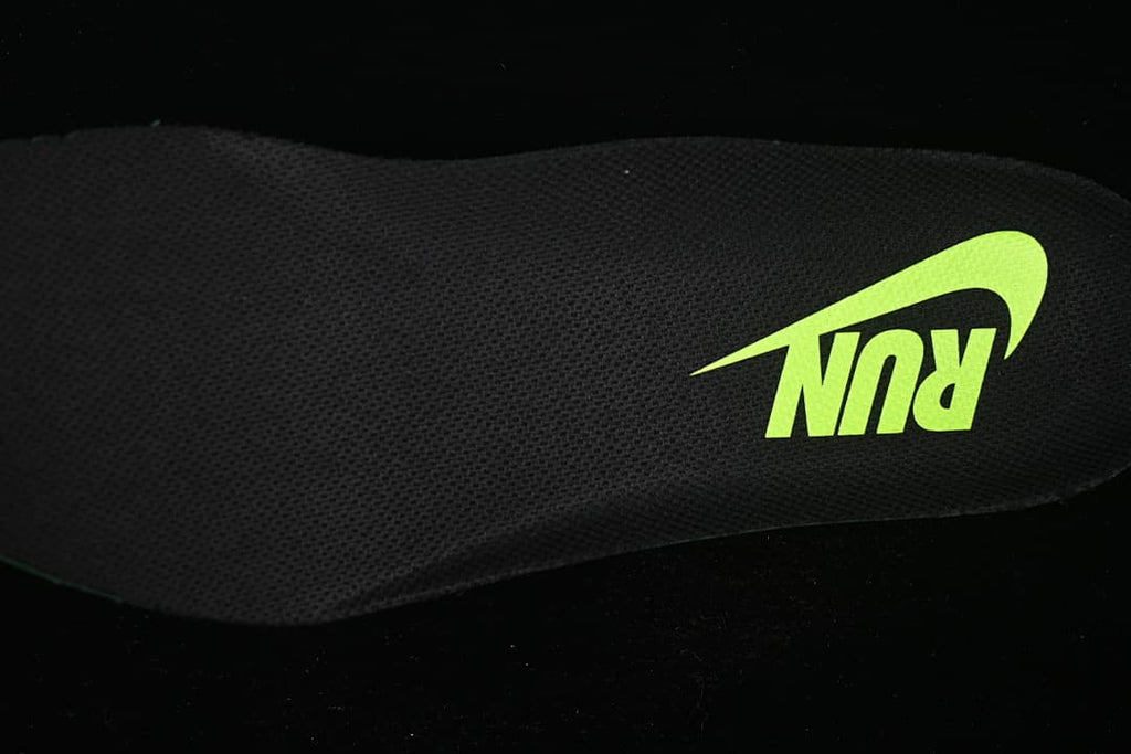 Close-up of a black textured shoe insert with a bright volt Nike graphic.