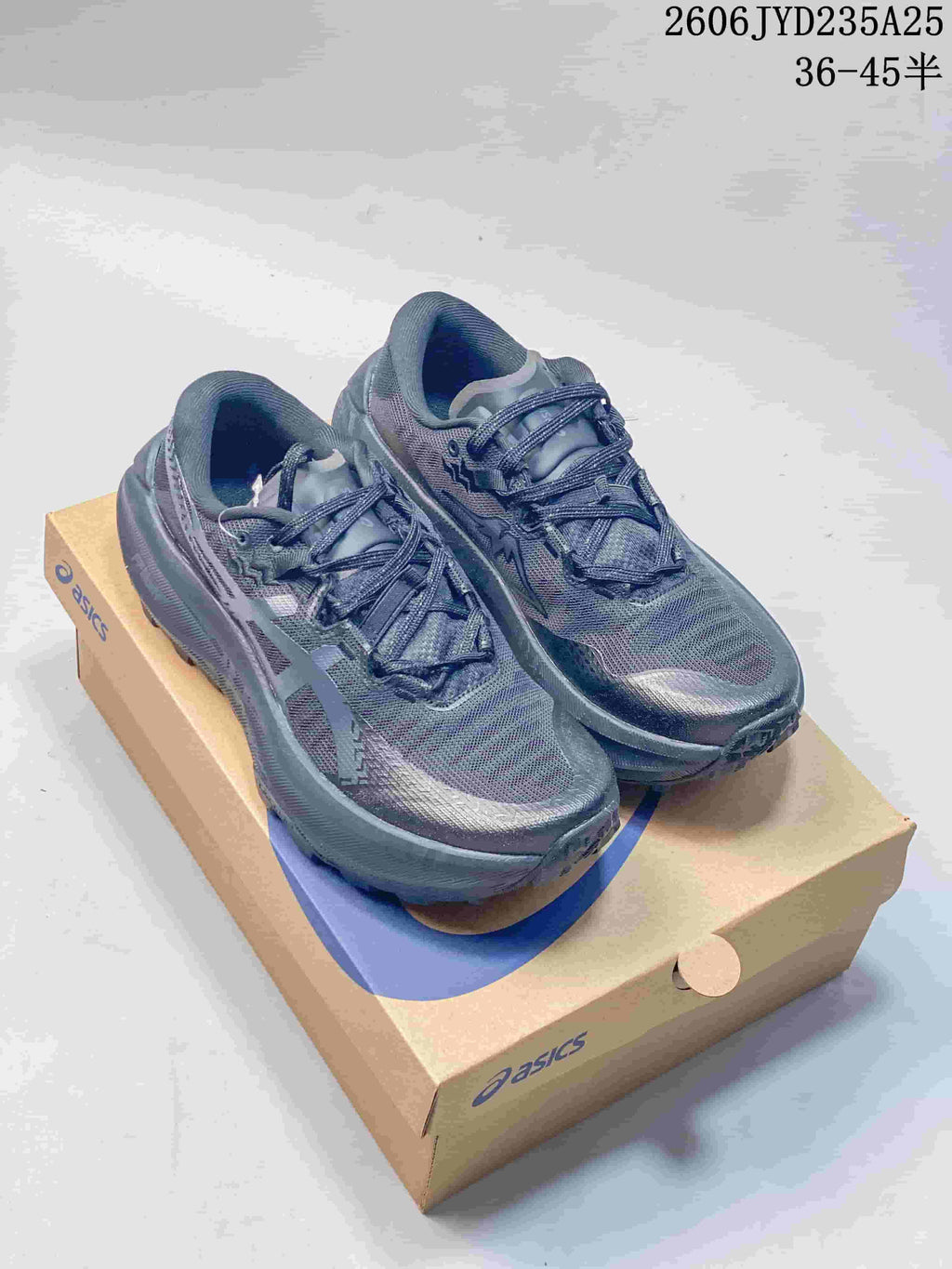 Pair of dark charcoal ASICS GEL-TRABUCO MAX 5 shoes on a shoe box.