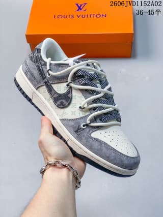 Angled view of a white and gray Louis Vuitton x Nike Dunk Low sneaker held above an orange shoe box; the image shows the patterned overlays, Swoosh branding, laces, and perforated toe.