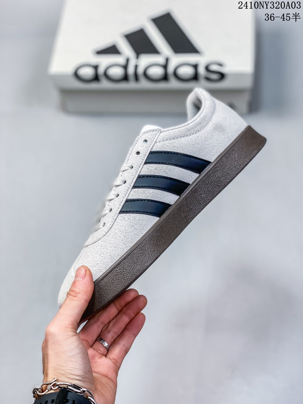 Side profile of the light grey sneaker with dark stripes and a brown-toned outsole