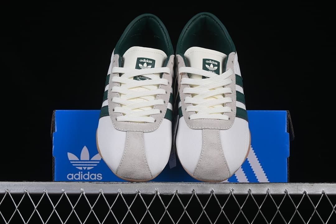 Front view of the pair of white and green Adidas Tokyo sneakers on a blue shoebox