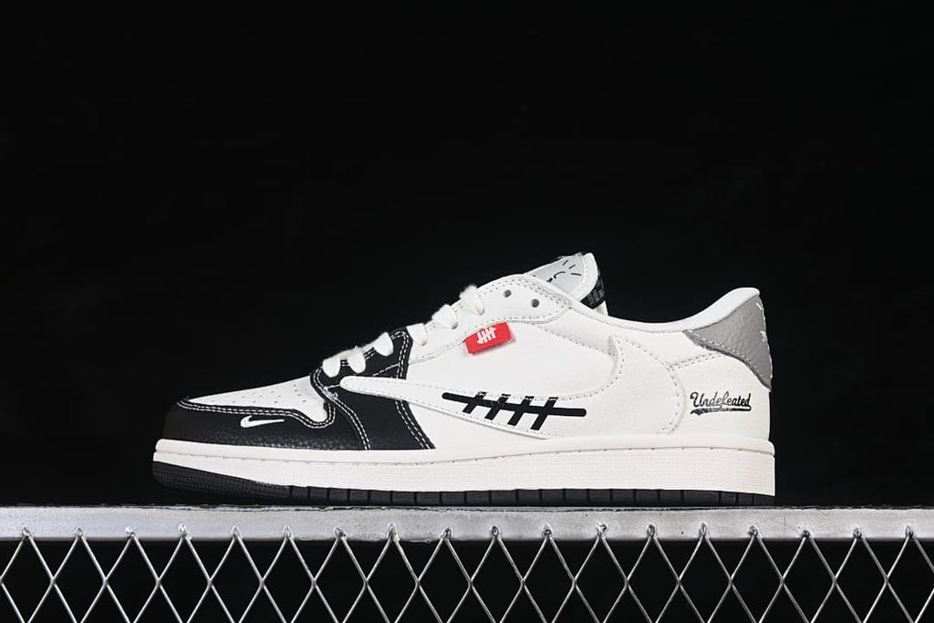 Side profile of an off-white low-top sneaker with black forefoot overlays, grey heel accent, and decorative side graphics.