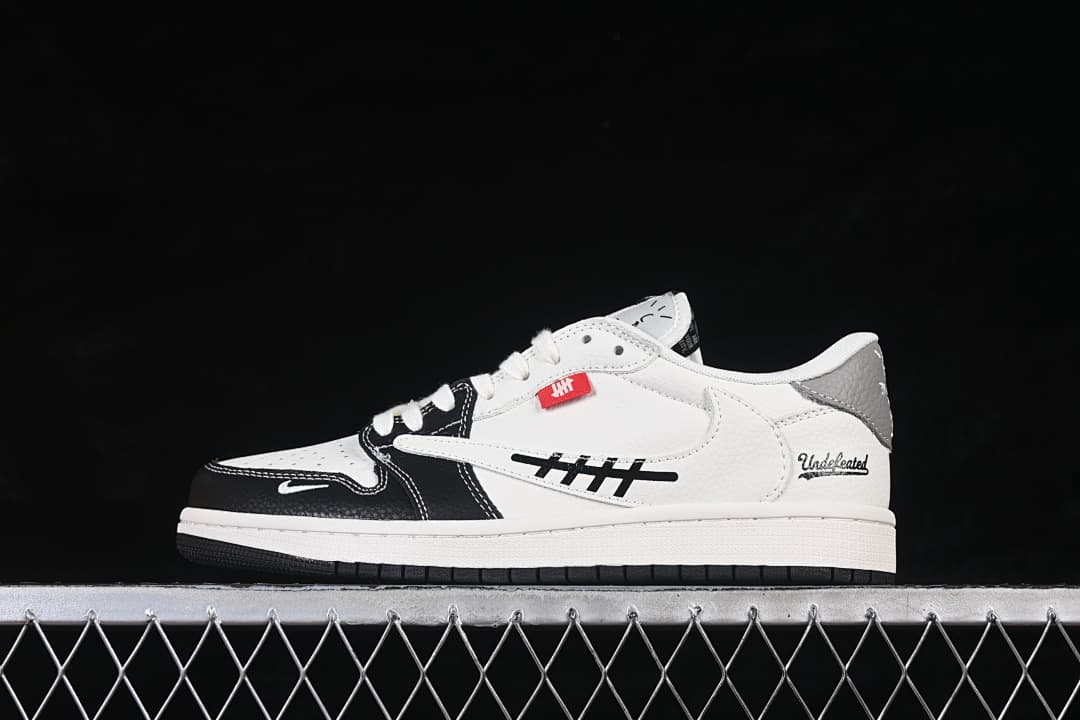 Side profile of an off-white low-top sneaker with black forefoot overlays, grey heel accent, and decorative side graphics.