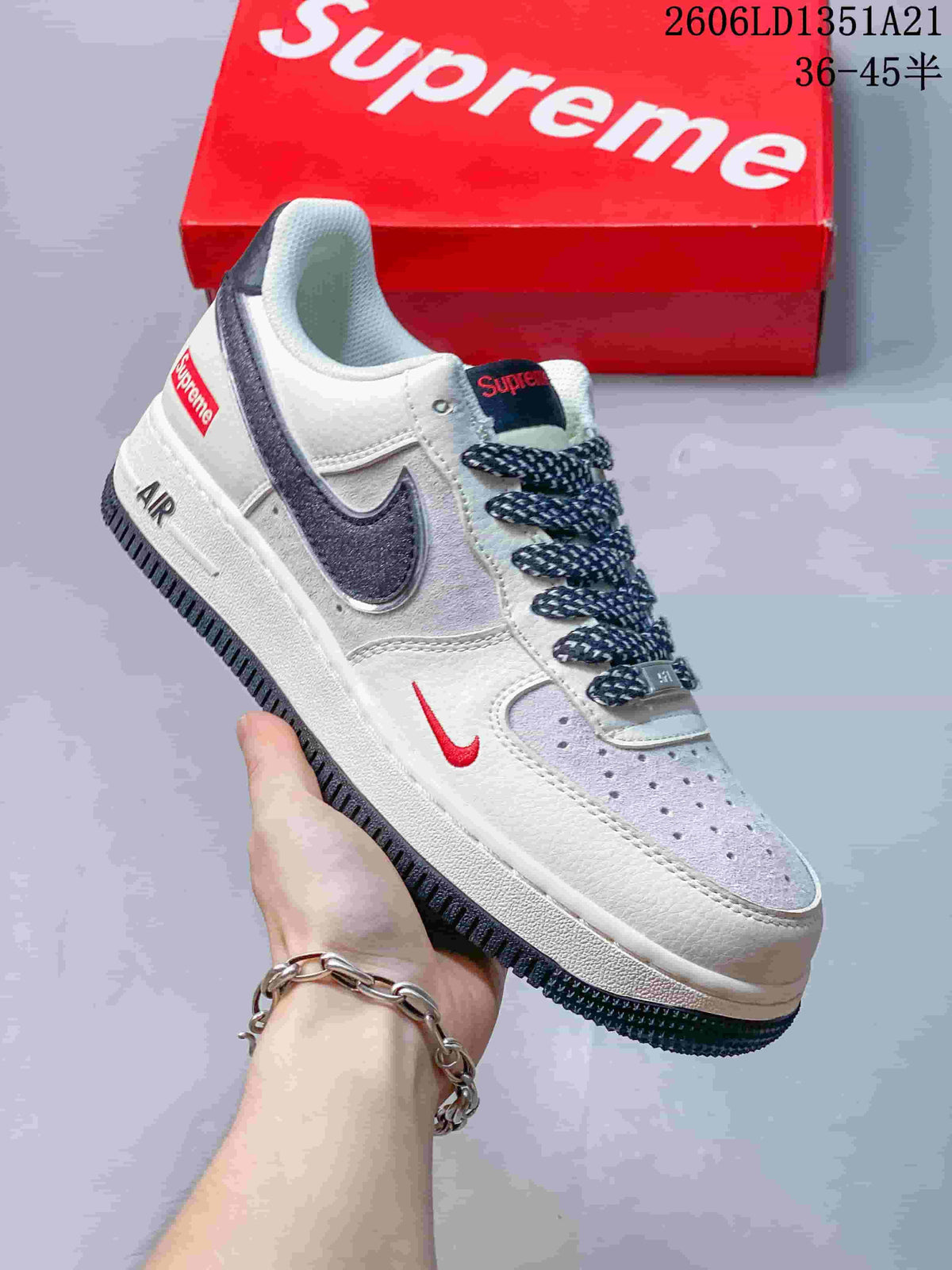 Angled view of the white sneaker with dark Swoosh, patterned laces, and red details.