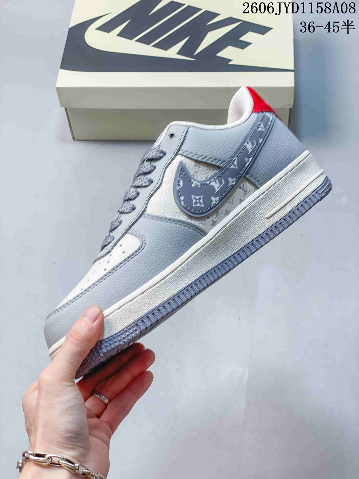 Side view of a gray and white low-top sneaker with patterned side panels and red heel accent