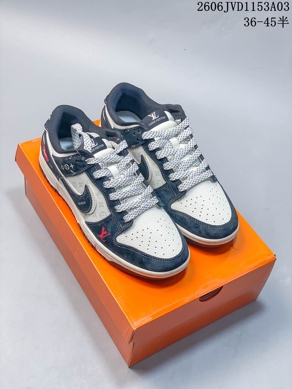Pair of navy and white low-top sneakers with patterned panels and layered Swoosh details on an orange box