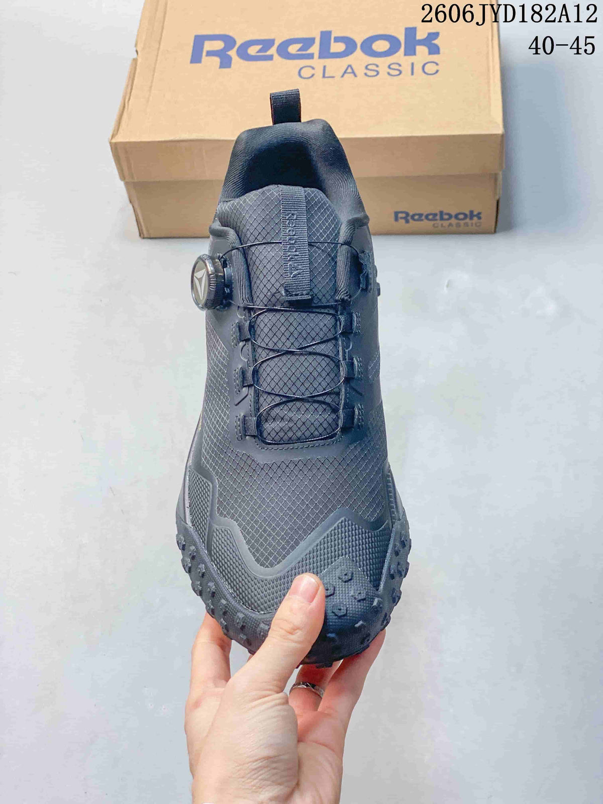 Front view showing the patterned upper and dial detail on a charcoal sneaker.