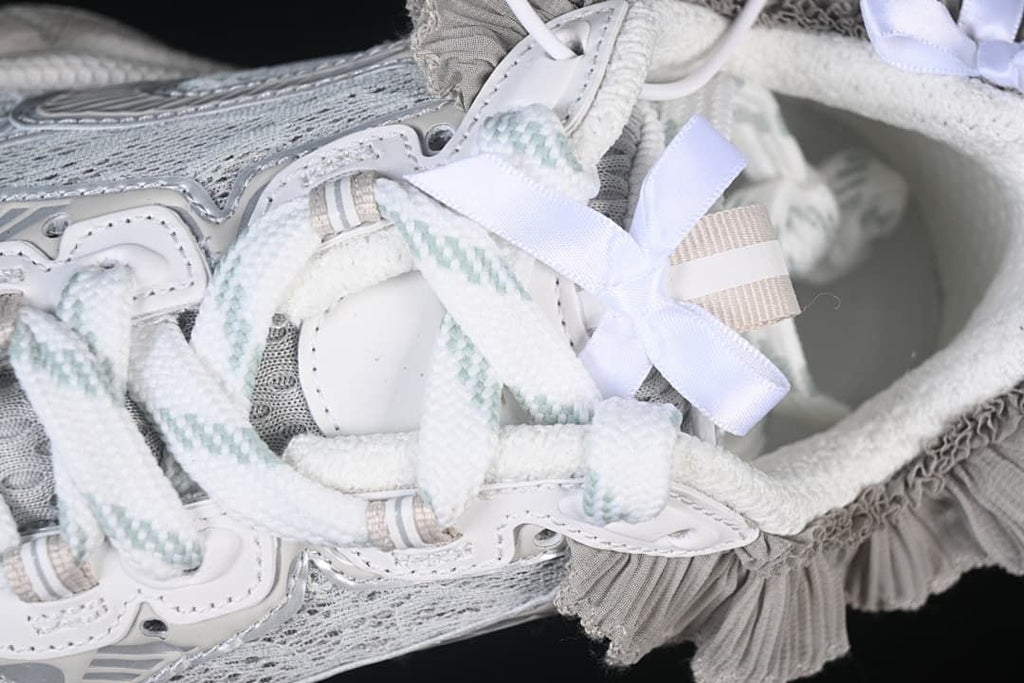 Close-up of the laces, pale ribbon bow, and gray ruffle trim