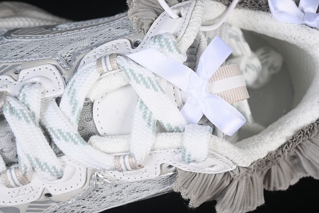 Close-up of the laces, pale ribbon bow, and gray ruffle trim