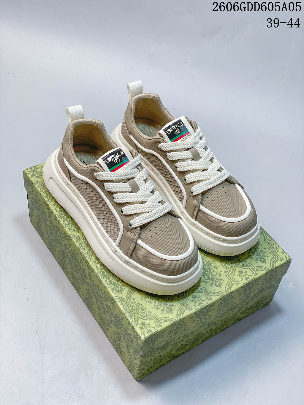 Pair of beige lace-up sneakers with white piping, textured side panels and thick white soles.