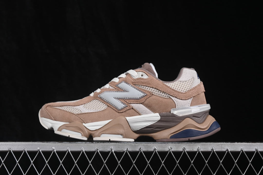 Side profile of a New Balance 9060 sneaker showing the large side logo, mesh panels, and multicolor sole.