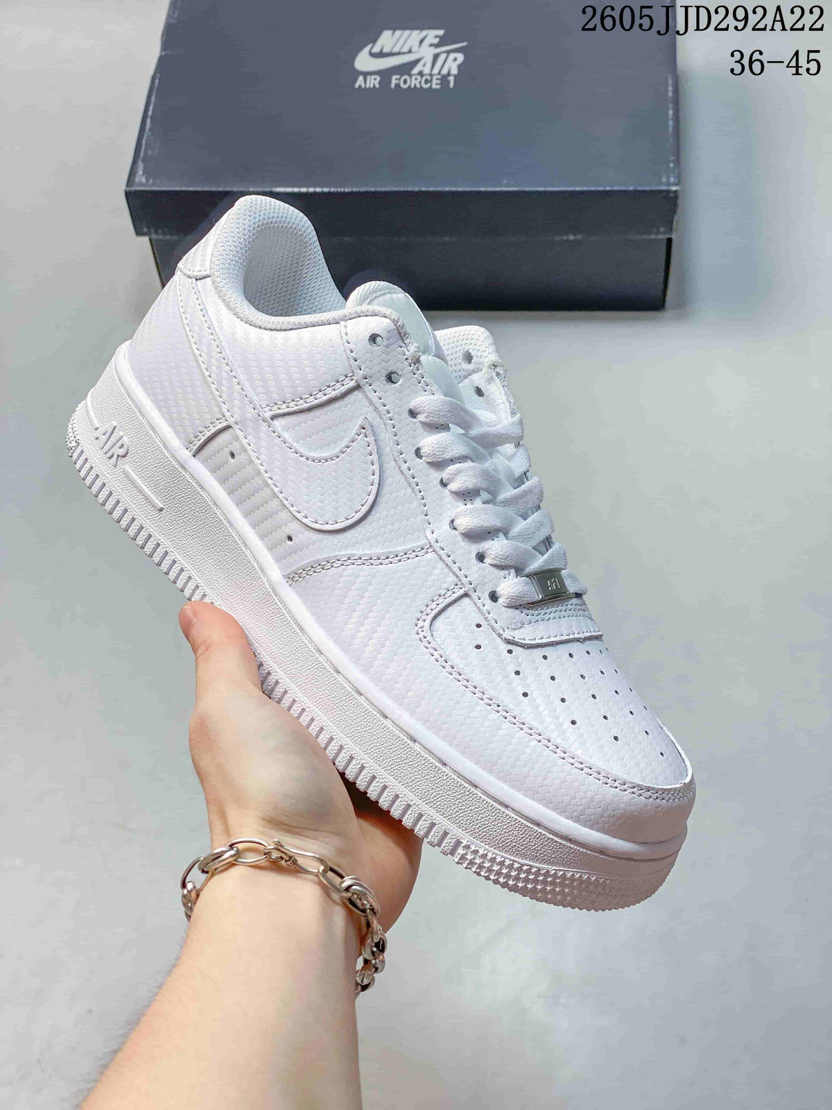 White low-top sneaker with a subtle textured pattern and layered panels.