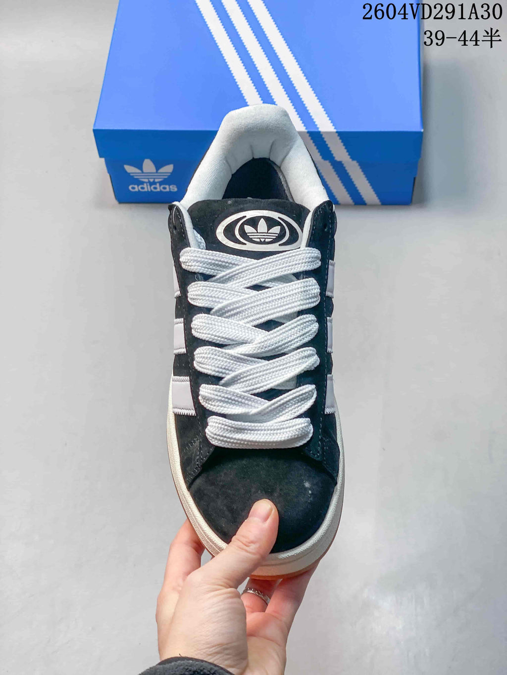 Front view of a dark Campus sneaker with white laces and a padded light-colored collar