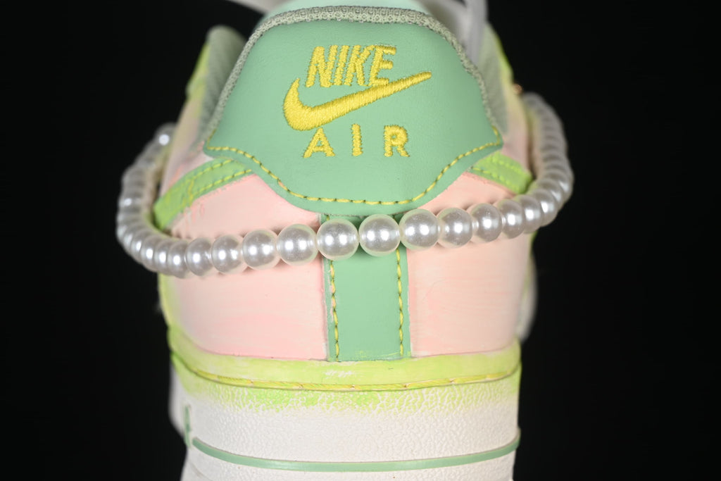 Rear view of the sneaker with green heel tab, pink panels, and pearl-like trim