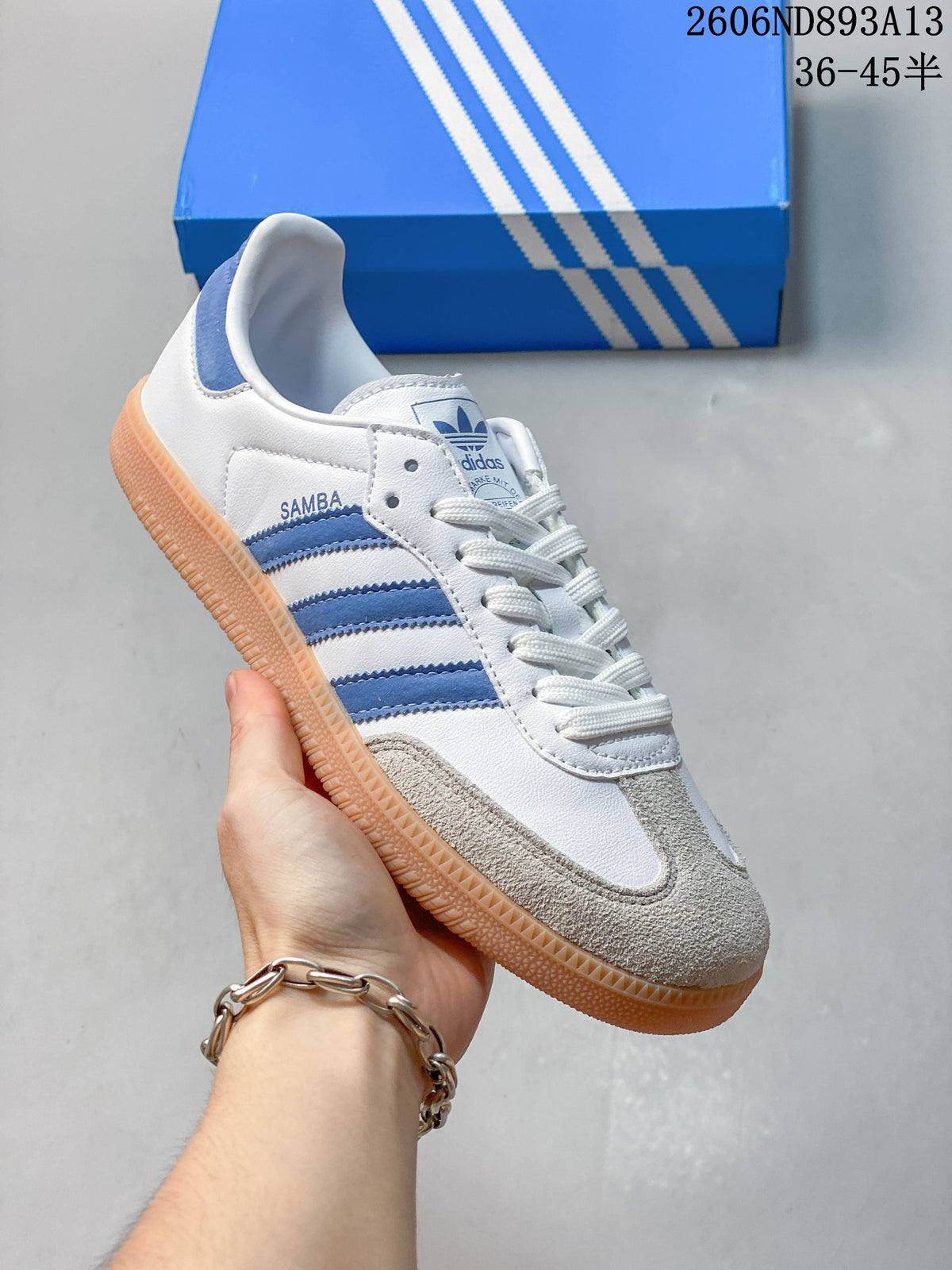 Angled side view of the sneaker showing the Samba name, blue stripes, and gum-colored outsole.