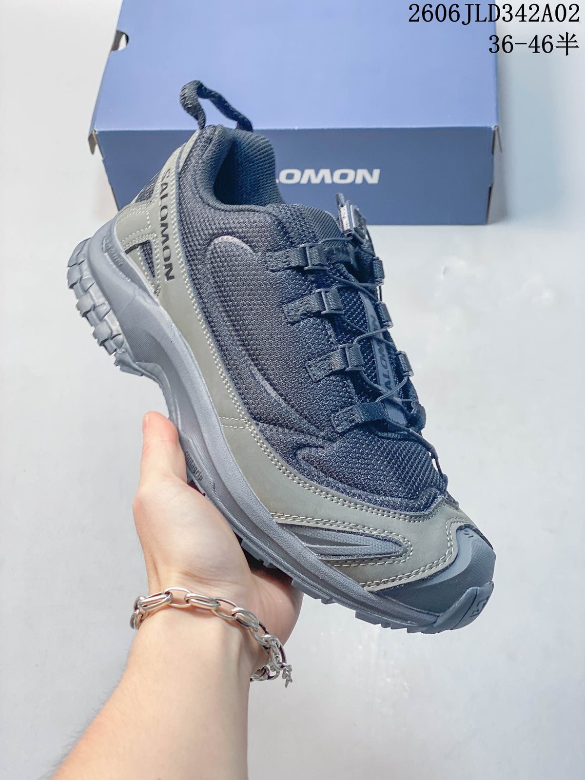 Angled side view of a gray Salomon trail shoe with a lugged outsole.