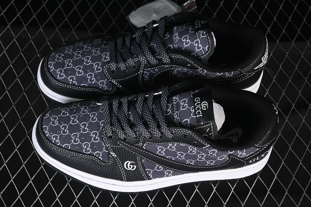 Overhead view of a pair of black low-top sneakers with patterned panels, black laces, and white midsoles
