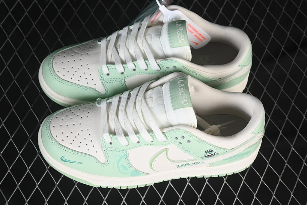 Top view of a pair of mint green and off-white Nike SB Dunk Low sneakers with perforated toes and Labubu-themed details