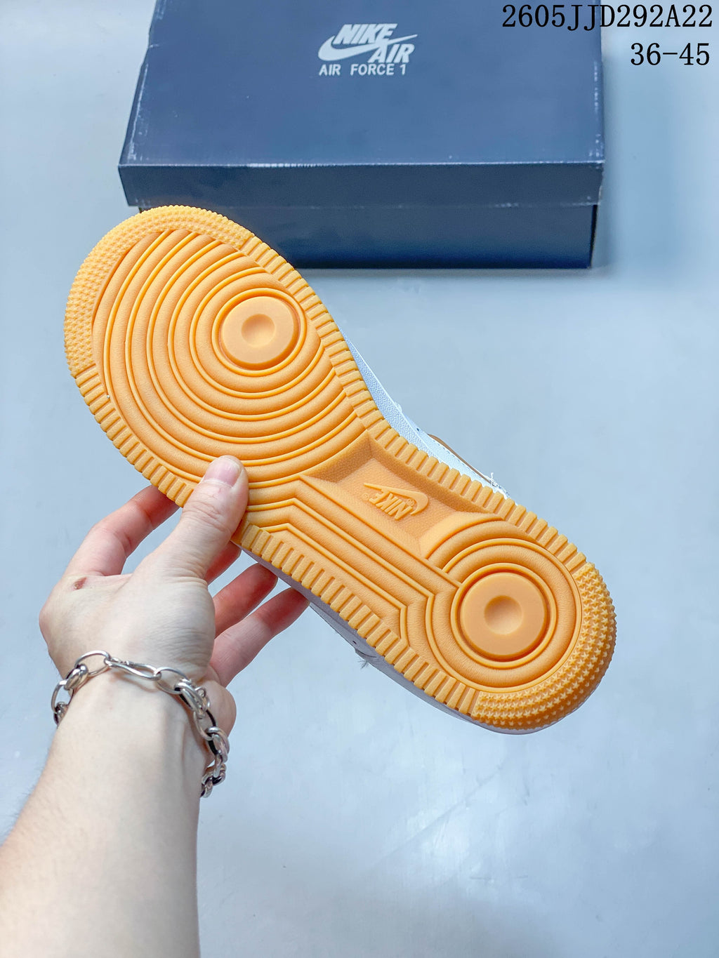 Underside of the sneaker showing an orange outsole with circular tread patterns